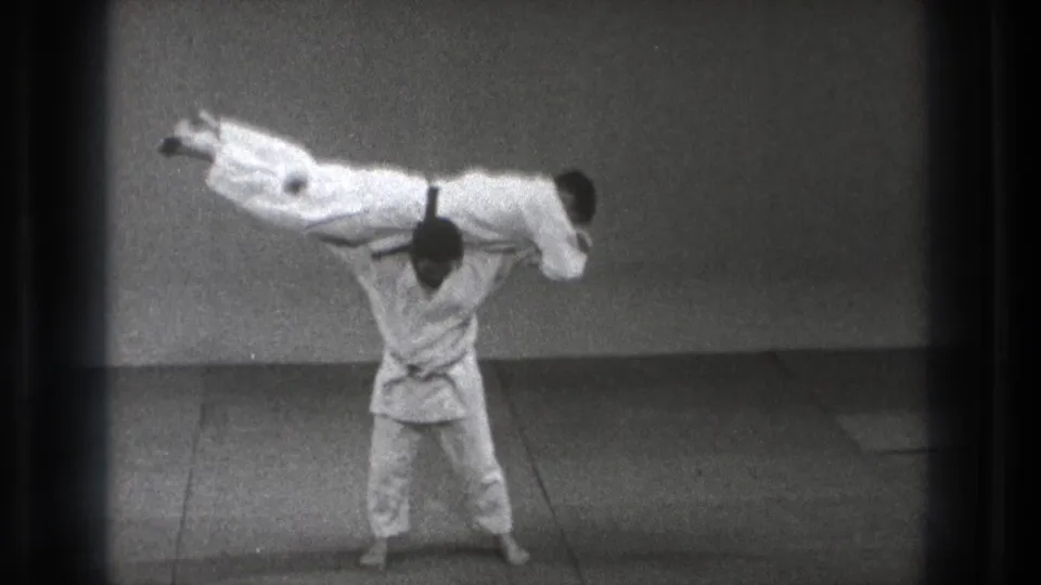 The final frame shows the judo demonstration at its peak, with one uniformed man supporting the other horizontally in the sparse Tokyo practice space.