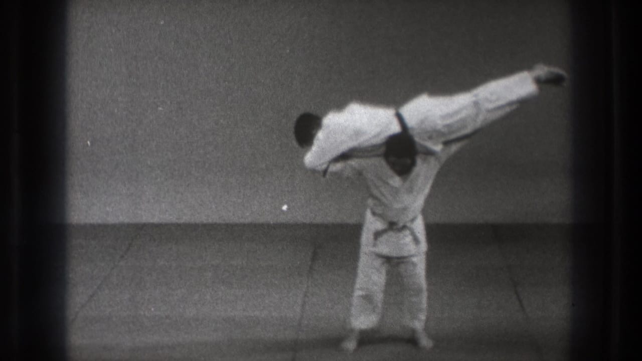 The Tokyo martial arts demonstration shows one gi-clad practitioner holding his partner nearly horizontal in a lift.