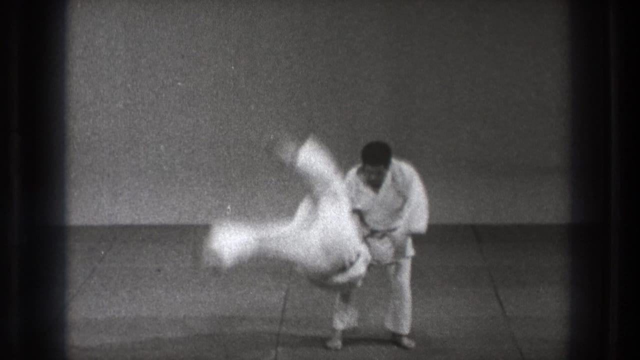 In the 1971 Tokyo home-movie frame, a judo practitioner completes a fast throw as the other man rotates through the air.
