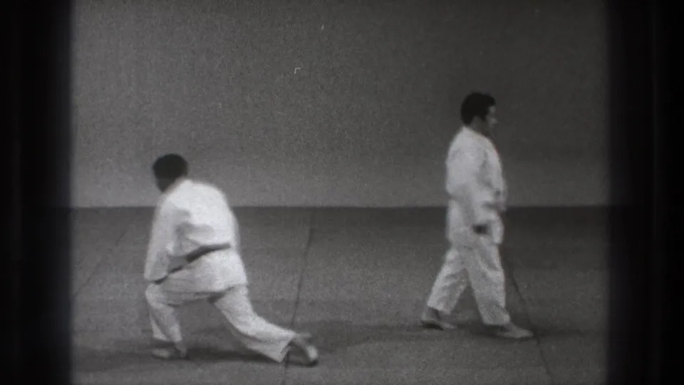 1971 Tokyo martial arts footage with one barefoot participant crouching as another moves across the mat.