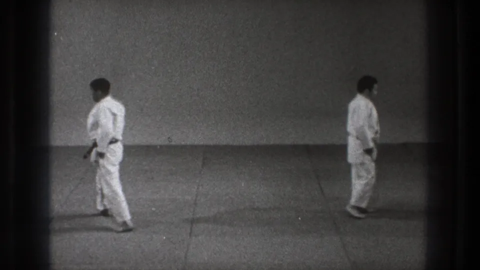 1971 Tokyo 8mm frame showing two martial arts participants standing apart in a simple training space.