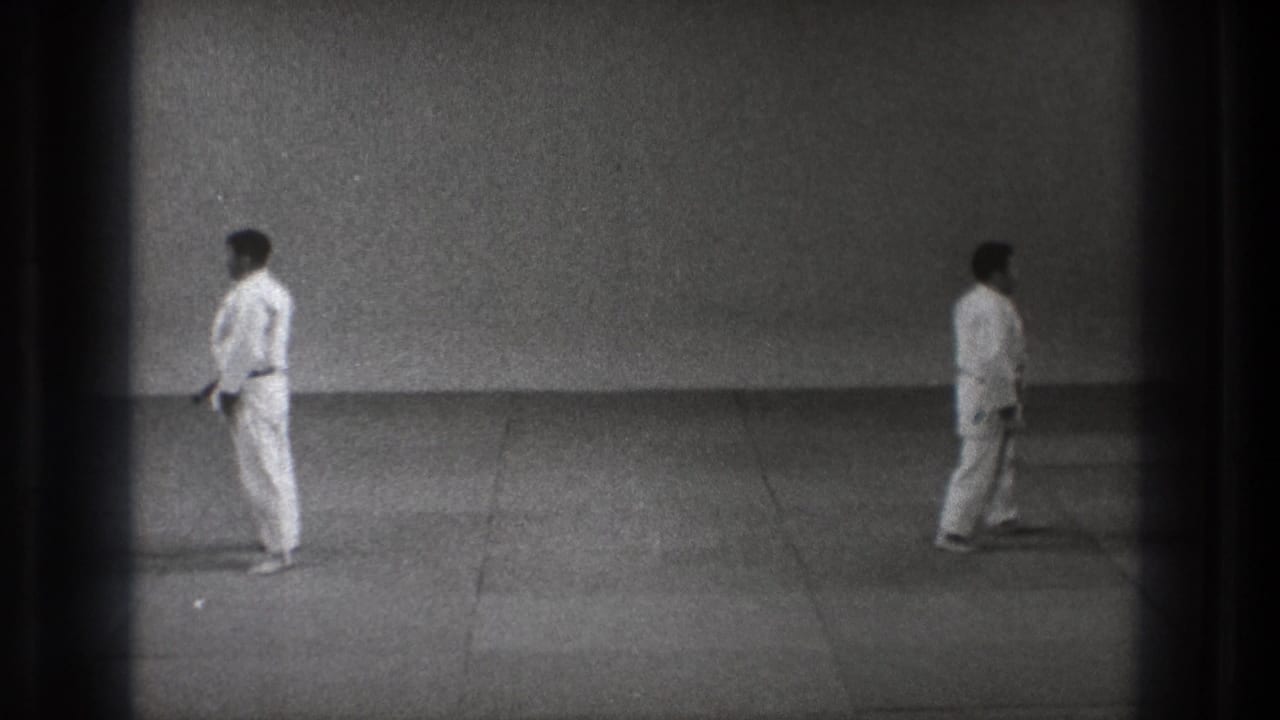 1971 Tokyo martial arts frame with two barefoot men in white uniforms standing on a plain mat.