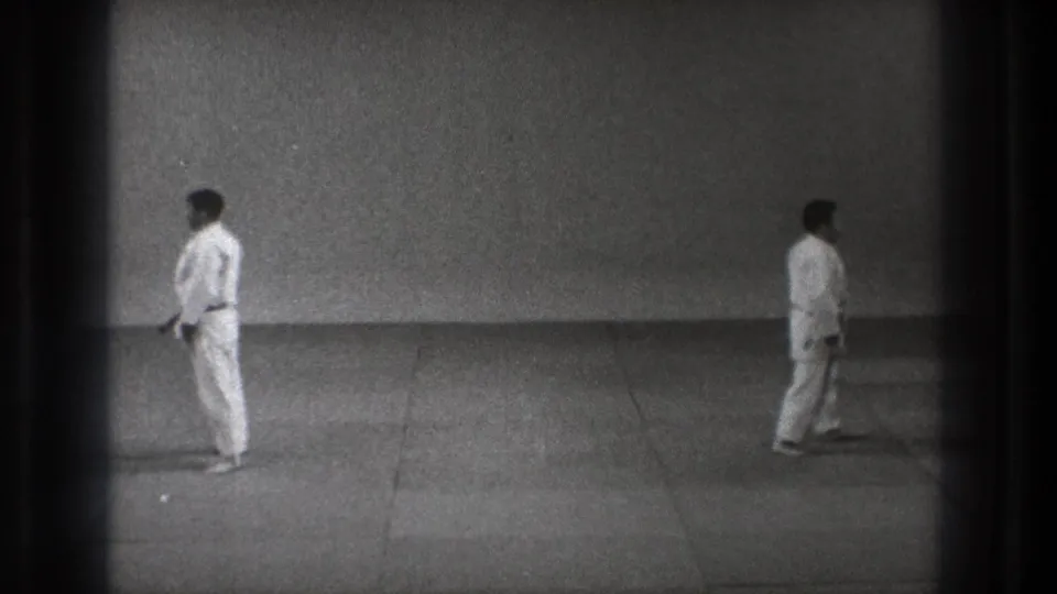 1971 Tokyo martial arts frame with two barefoot men in white uniforms standing on a plain mat.