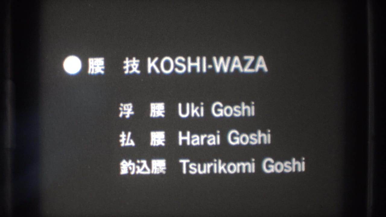 Bilingual martial-arts title card repeats KOSHI-WAZA with three listed hip throw techniques on a dark film frame.