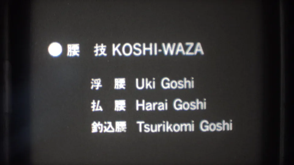 Bilingual martial-arts title card repeats KOSHI-WAZA with three listed hip throw techniques on a dark film frame.