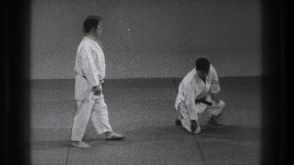 In the supplied 1971 Tokyo clip, two adult men in white gi practice on mats as one stands and the other holds a low crouched stance.