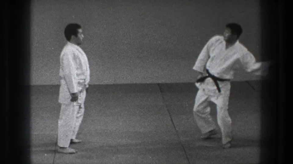 A black-belt practitioner moves quickly toward his partner during a karate or martial arts demonstration in the 1971 Tokyo footage.