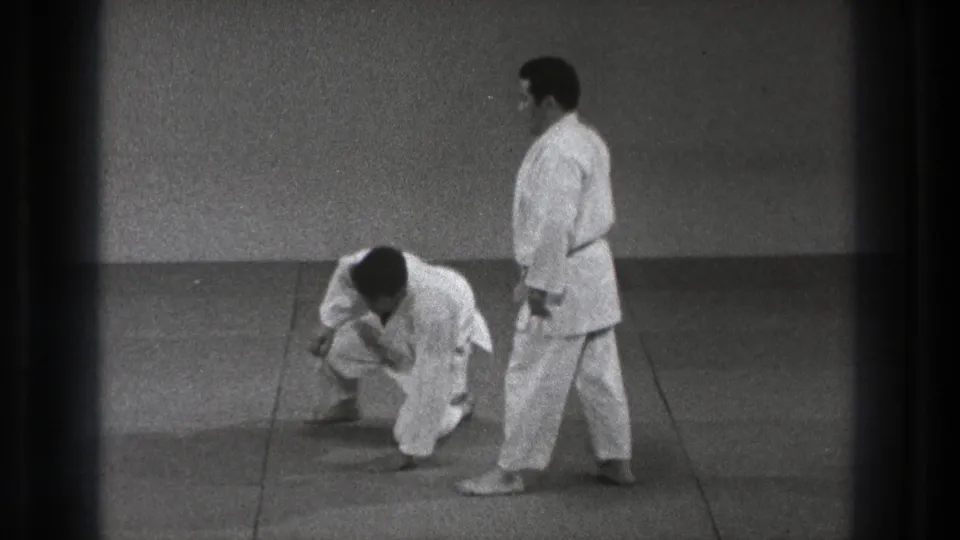 The downed judo practitioner begins to rise as the partner stands nearby in this 1971 Tokyo martial arts scene.