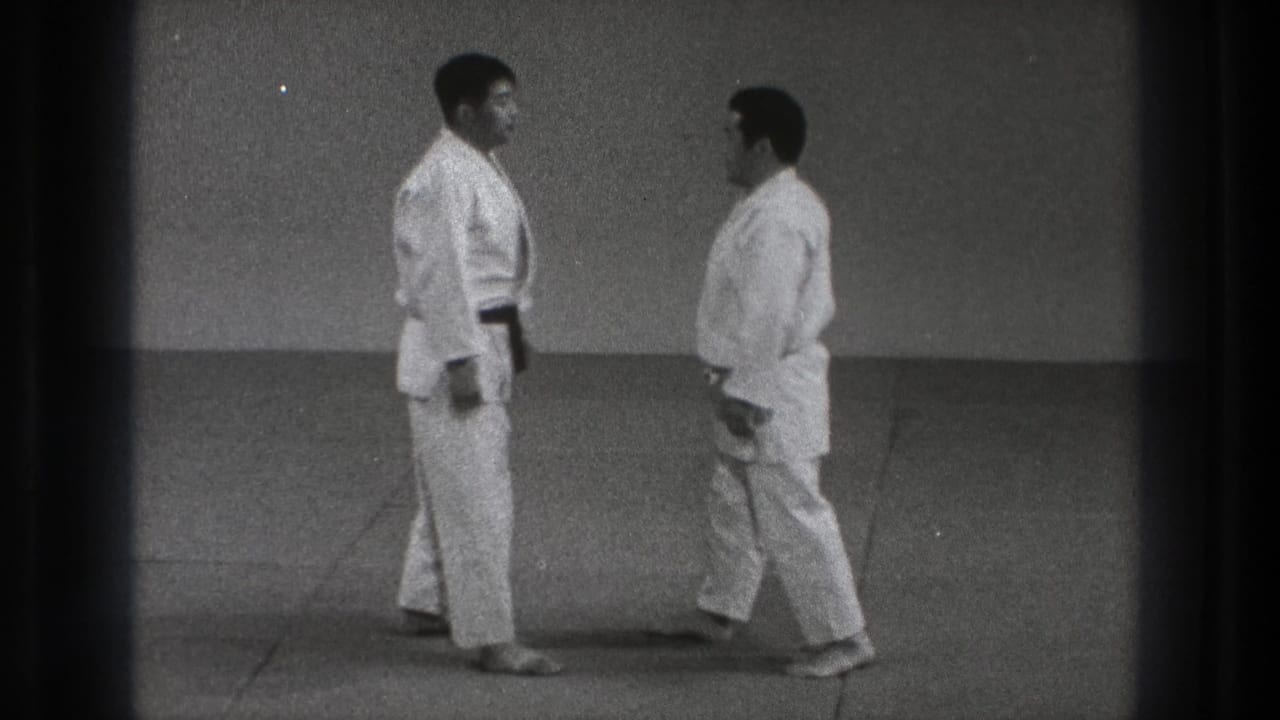 Two judoka in white gi approach each other on a dojo mat in archival 1971 Tokyo footage.