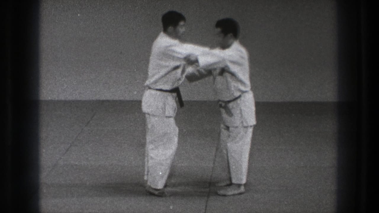 Two men in white gi grip each other while standing on a mat.