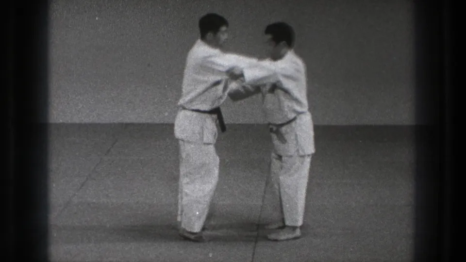 In 1971 Tokyo footage, two men in martial arts uniforms face each other on a mat at the start of a throwing drill.