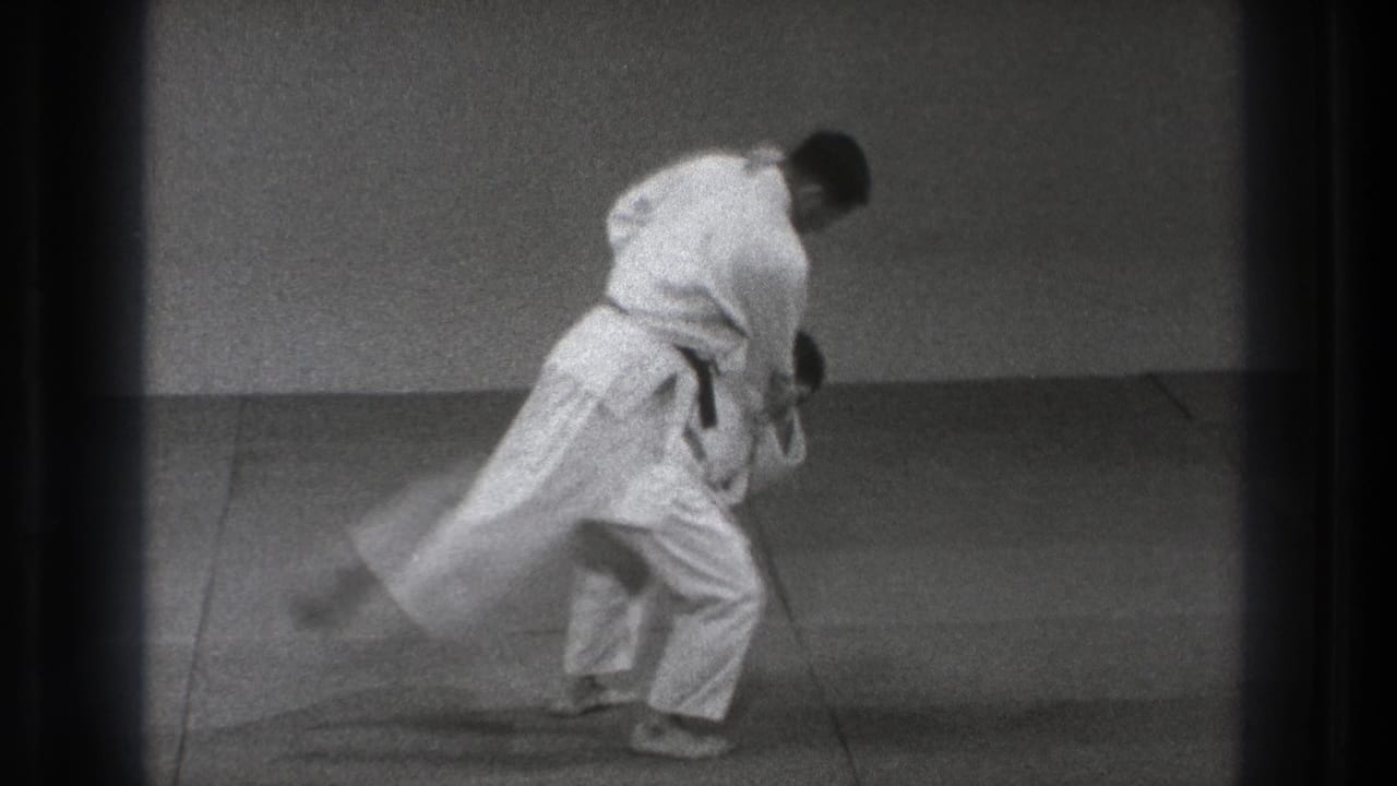 Two martial artists in white gi begin a judo throw on a mat.