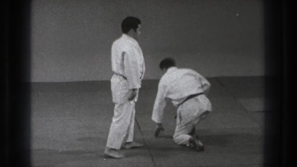 The sequence ends with one adult practitioner standing and the other pushing up from the mat after a judo-style throw in the Tokyo dojo.