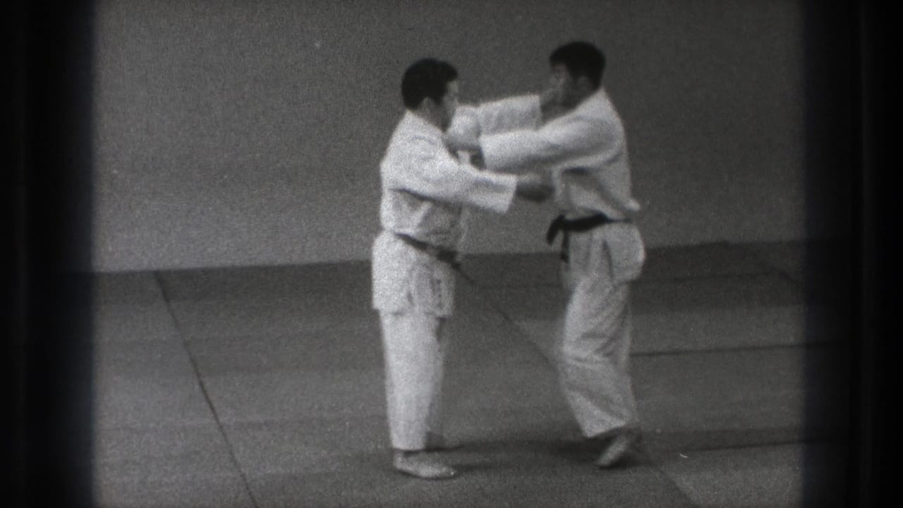 Two adult karate practitioners in a Tokyo dojo make controlled arm contact during a short 1971 training exchange.