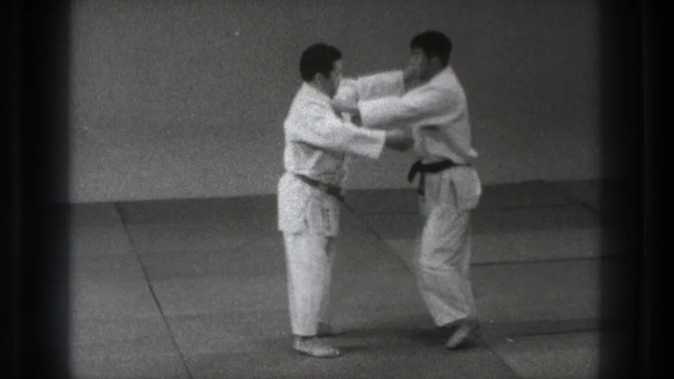 Two adult karate practitioners in a Tokyo dojo make controlled arm contact during a short 1971 training exchange.