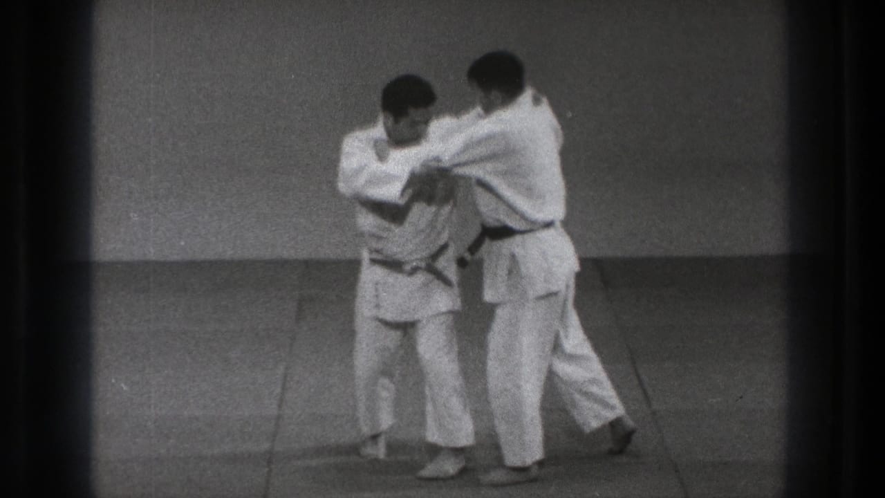 A practitioner turns inward during a paired martial arts movement as the other man stays in close contact.