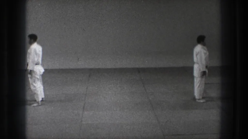 The final frame shows the two adult men separated on the grey mat in the 1971 Tokyo martial arts practice clip.