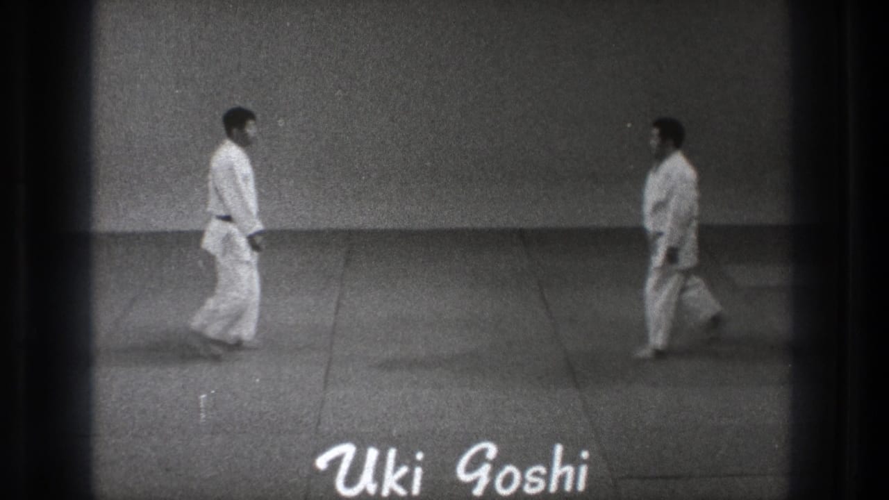 1971 Tokyo 8mm frame showing two gi-clad practitioners stepping toward each other on a dojo mat with 'Uki Goshi' text visible.