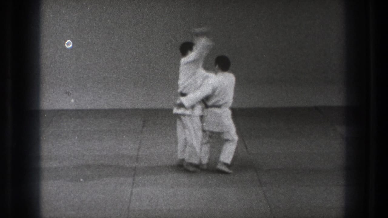 1971 Tokyo frame showing a judo hip throw in progress as one gi-clad practitioner lifts the other from the mat.