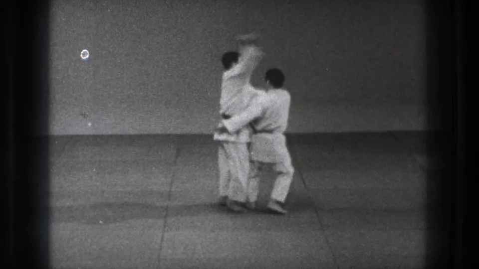 1971 Tokyo frame showing a judo hip throw in progress as one gi-clad practitioner lifts the other from the mat.