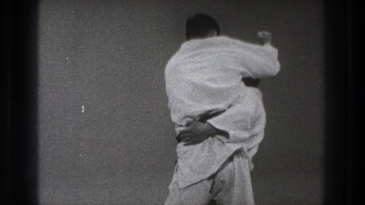 Two men in white gi grapple on a plain mat as one begins a throw.