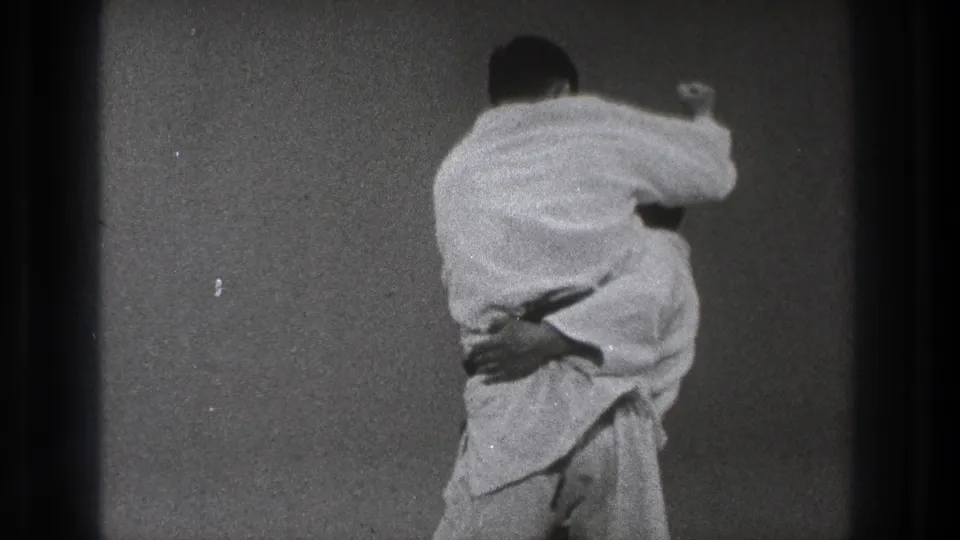 In Tokyo 1971 footage, two martial arts practitioners in white gi are locked together at close range during a throwing technique.
