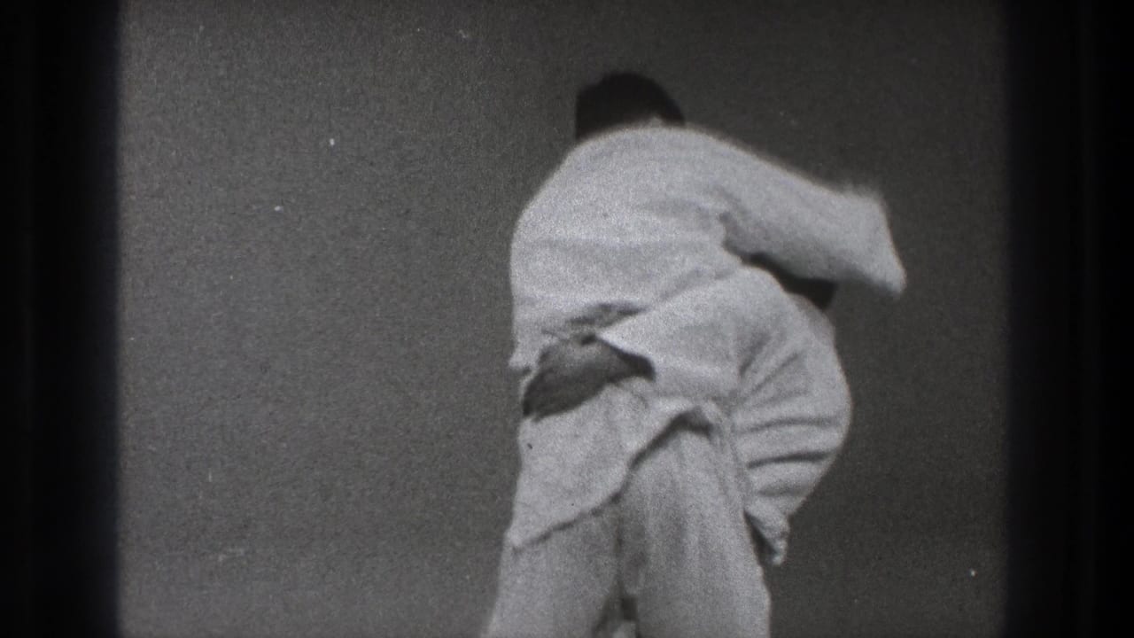 A Tokyo 1971 martial arts practice frame shows one man in a white gi turning his opponent through the middle of a throw.