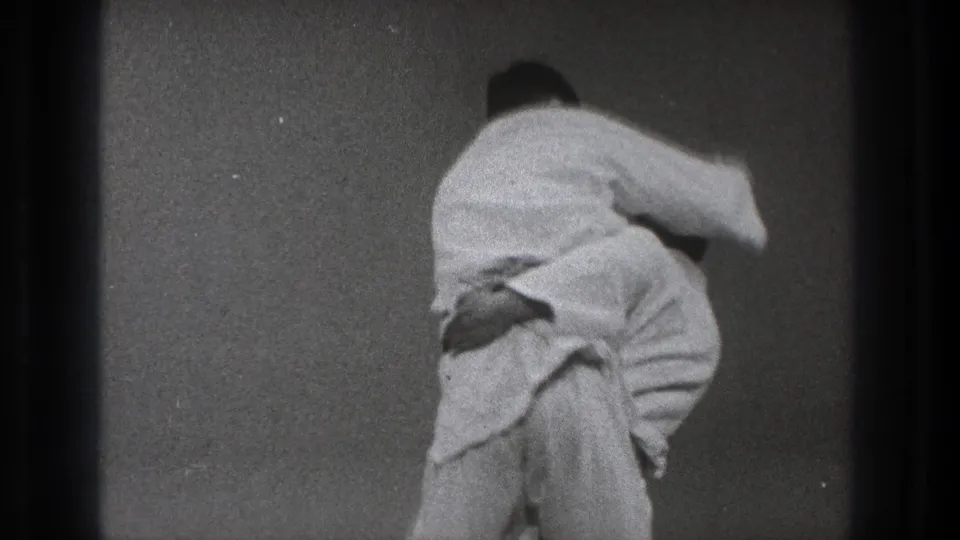 A Tokyo 1971 martial arts practice frame shows one man in a white gi turning his opponent through the middle of a throw.