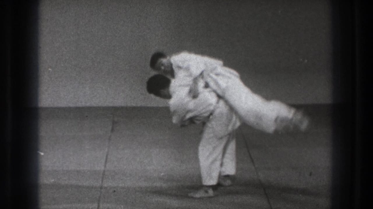 A 1971 Tokyo martial arts practice frame shows one man lifting his opponent across the hip on a simple mat.