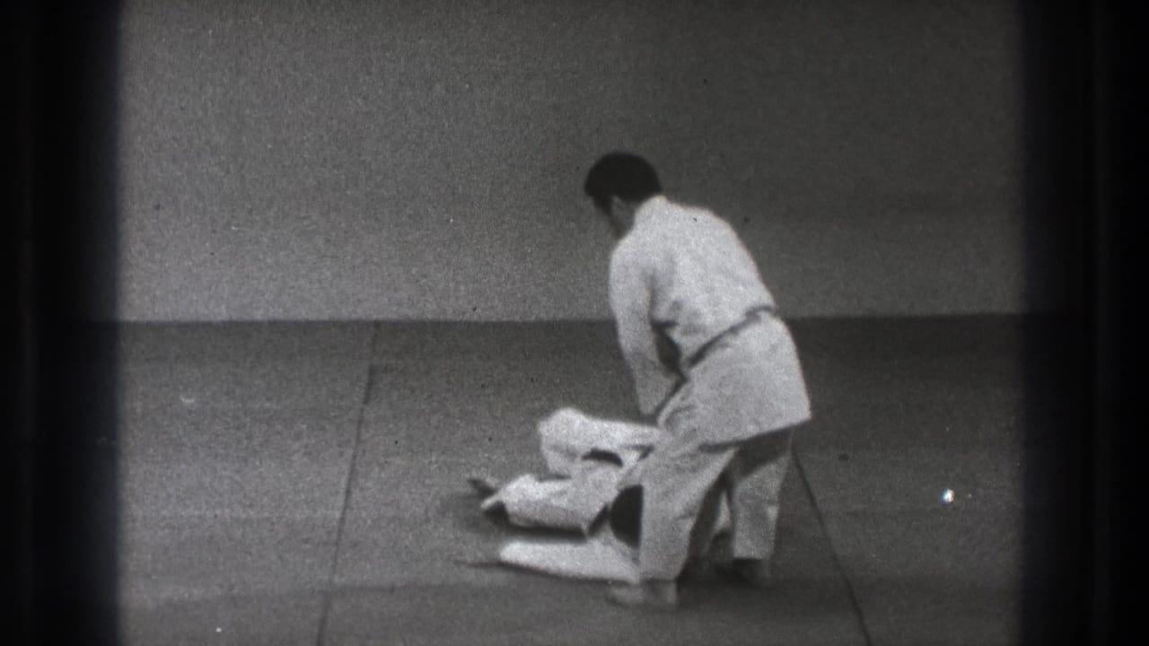 After the martial arts throw, one practitioner is down on the mat while the other stands nearby in the 1971 Tokyo footage.