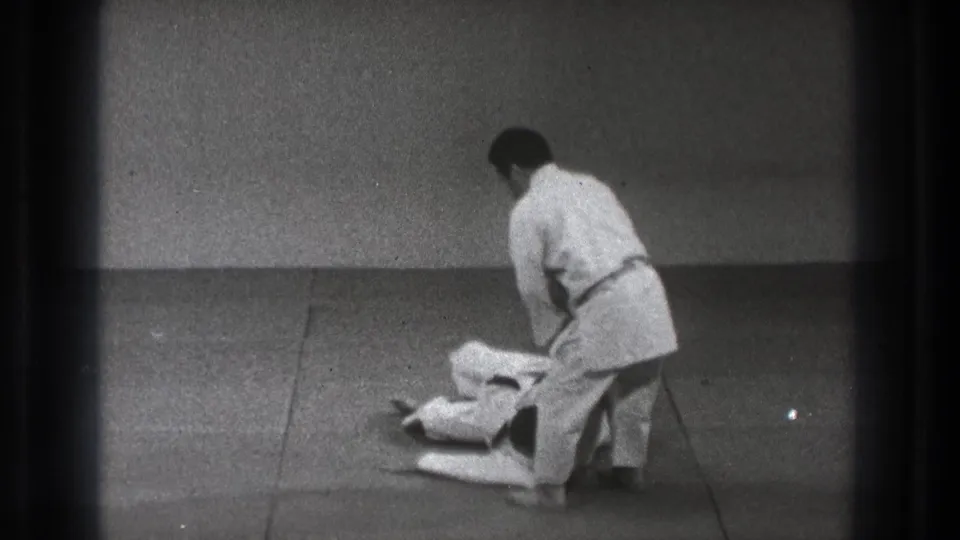 After the martial arts throw, one practitioner is down on the mat while the other stands nearby in the 1971 Tokyo footage.