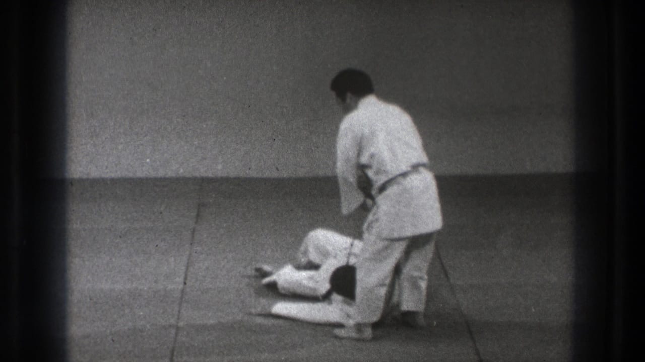 In 1971 Tokyo footage, two adult men practice martial arts on a tatami mat as one stands over the other after a floor technique.