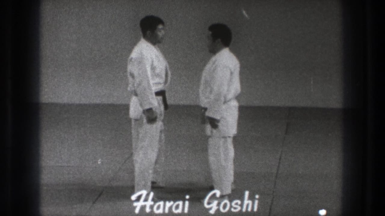 The two adult practitioners stand on the mat while a hand-lettered Harai Goshi title identifies the demonstrated technique.