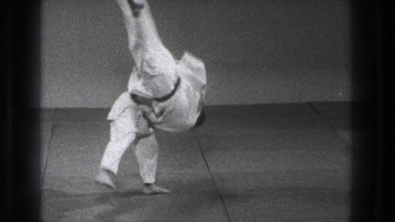 Tokyo 1971 frame of a karate practitioner completing a dynamic throw, with one leg elevated and an arm near the indoor mat for balance.