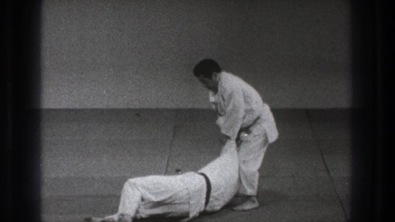 In the 1971 Tokyo martial arts demonstration, one man stands over a partner who has been taken down on the mat.