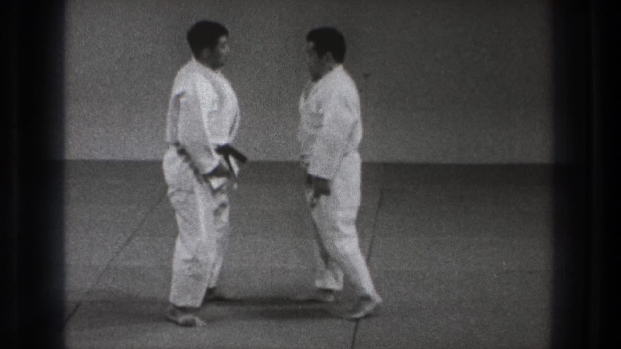 Two men in white judogi stand facing each other on a mat.