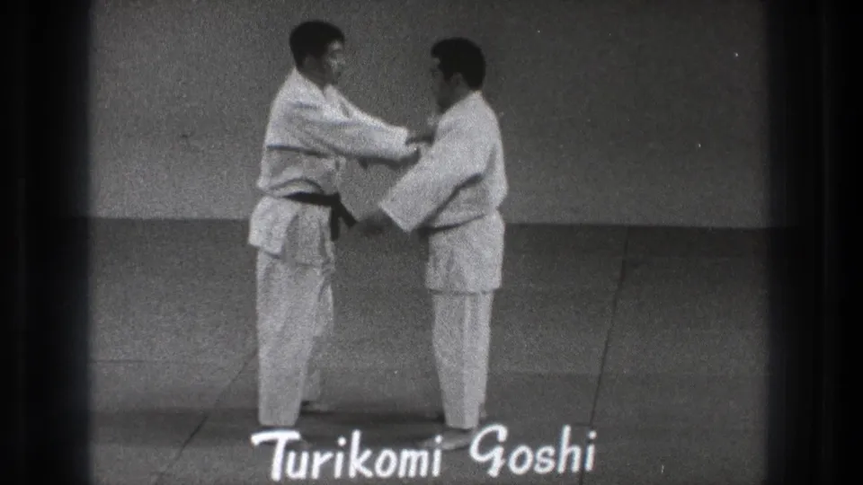 A 1971 Tokyo judo demonstration shows one practitioner holding his partner's lapel beneath the handwritten label Turikomi Goshi.