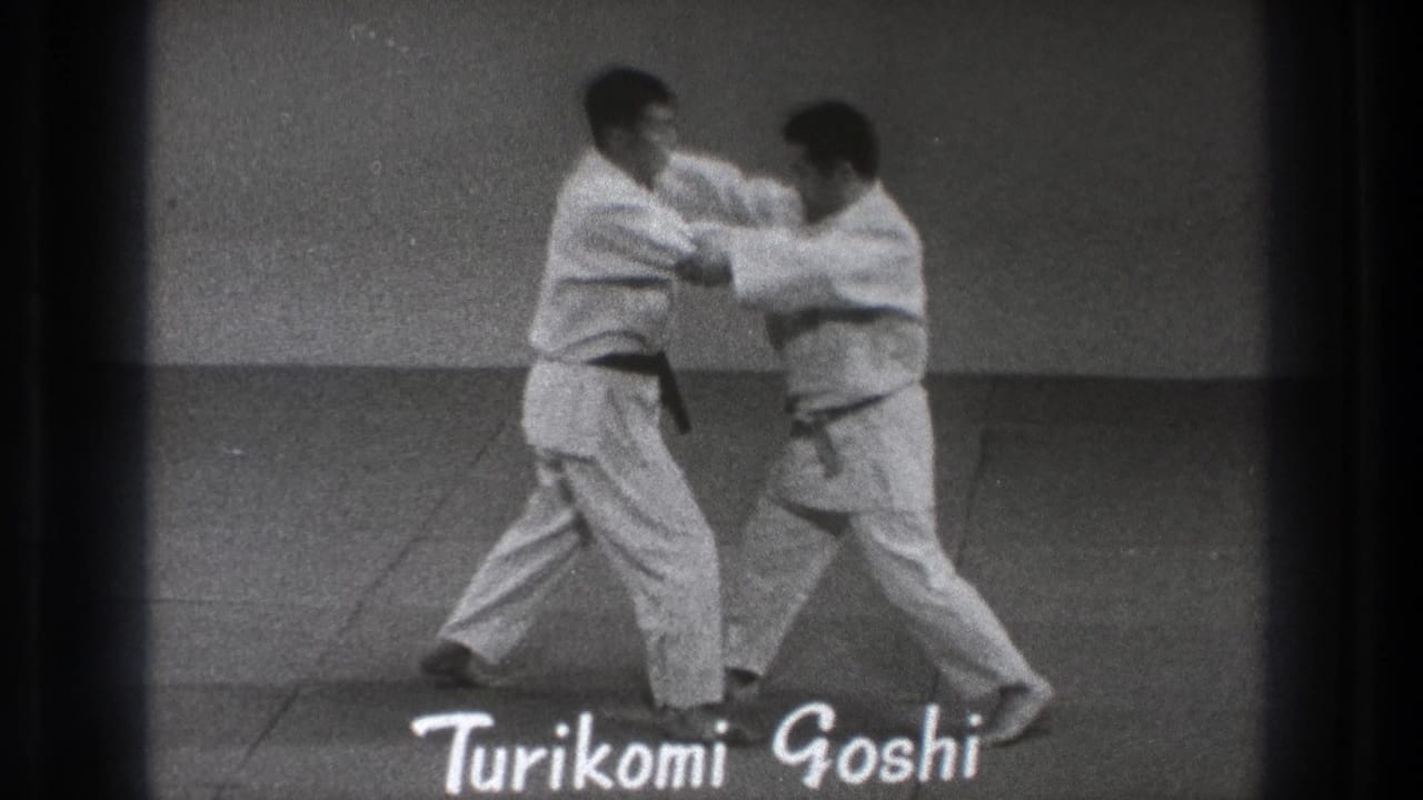 Two men in gi grip each other on a mat as the title Turikomi Goshi appears.