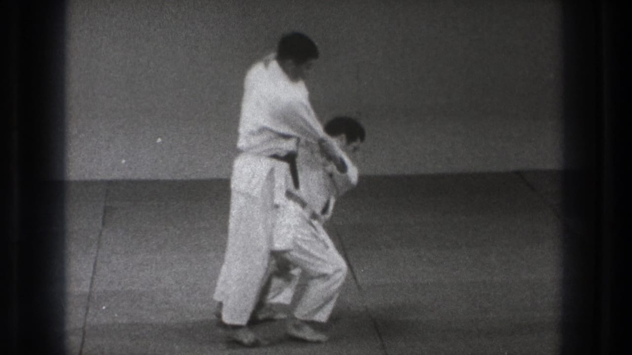 One adult practitioner turns his body in front of the other during the 1971 Tokyo Turikomi Goshi demonstration, preparing the hip throw.