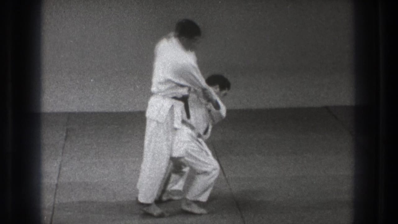 A black-belt practitioner grips his partner while starting a throw.