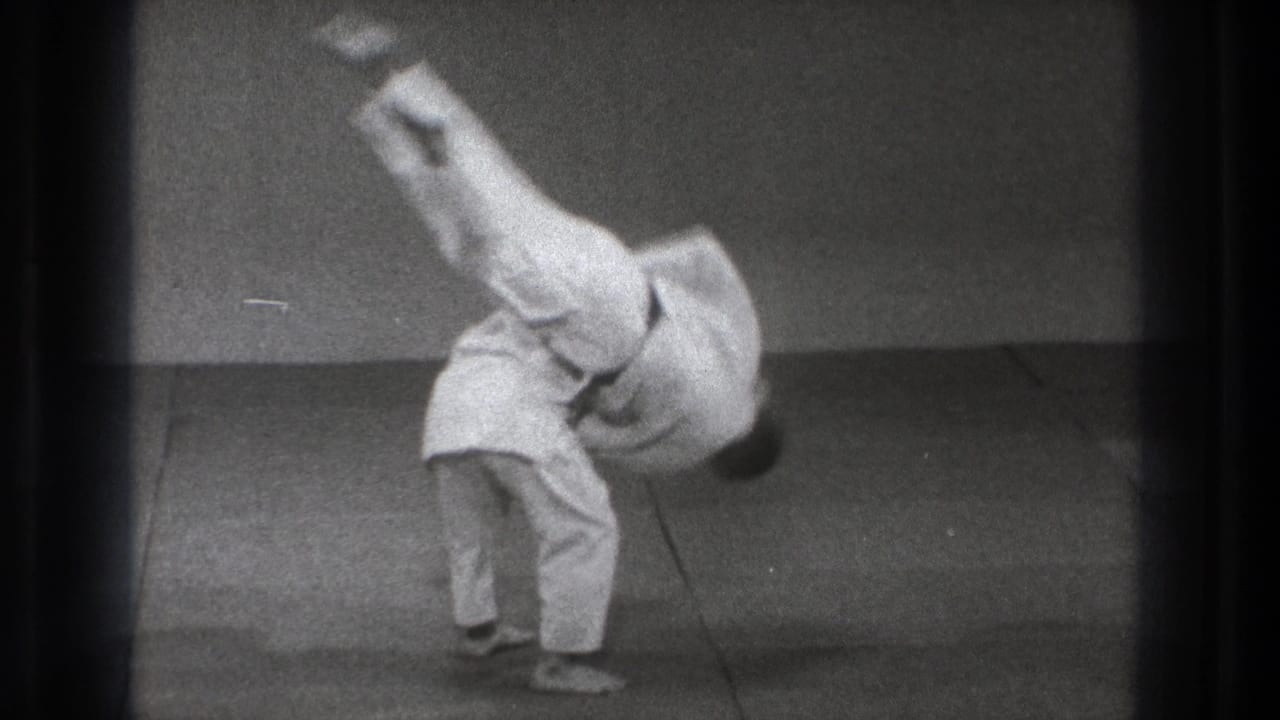 A practitioner is airborne and inverted as the throw reaches its most dynamic point in the 1971 Tokyo practice scene.