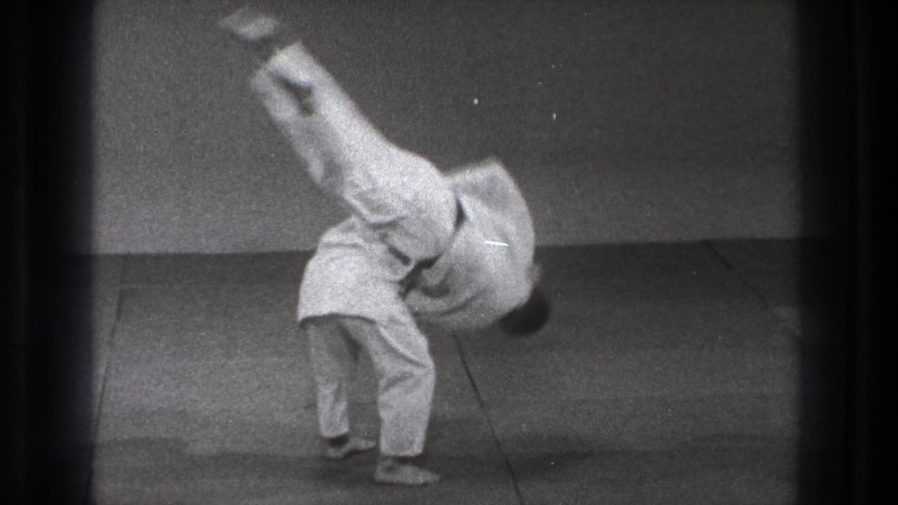 The black-and-white 8mm frame shows the partner still inverted over the mat during the karate throw in Tokyo, 1971.
