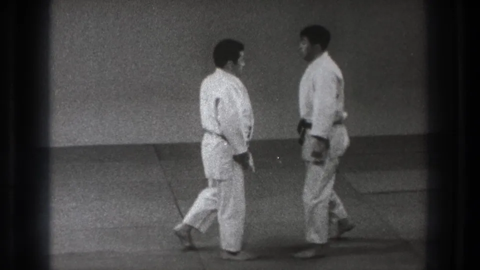 In 1971 Tokyo home-movie footage, two men in white judo uniforms face each other on a dojo mat.