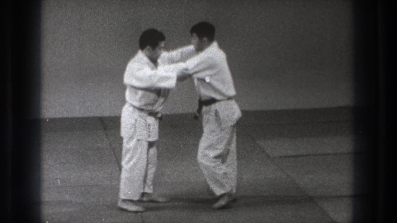 Two men in white martial-arts uniforms grip each other on a mat.