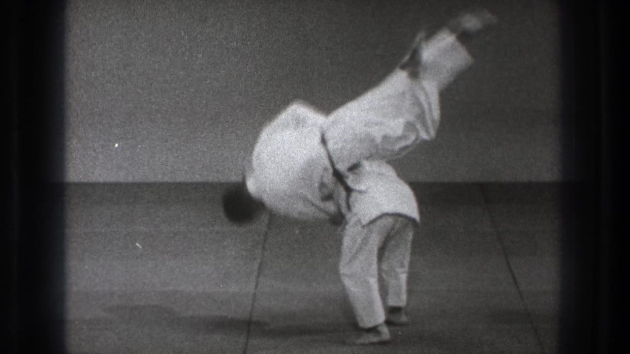 A man in a white judogi is airborne over his partner during a slow-motion judo throw in Tokyo, 1971.