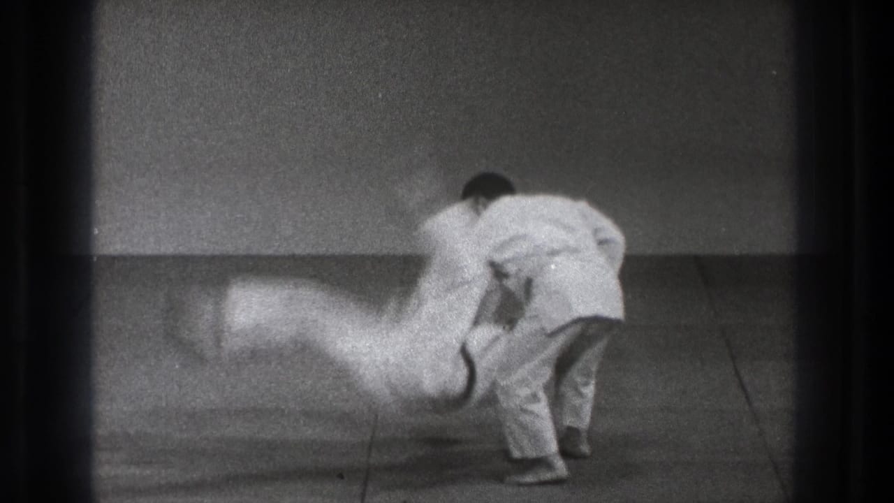 The thrown practitioner blurs downward toward the mat while his partner controls the motion in the 1971 Tokyo judo footage.