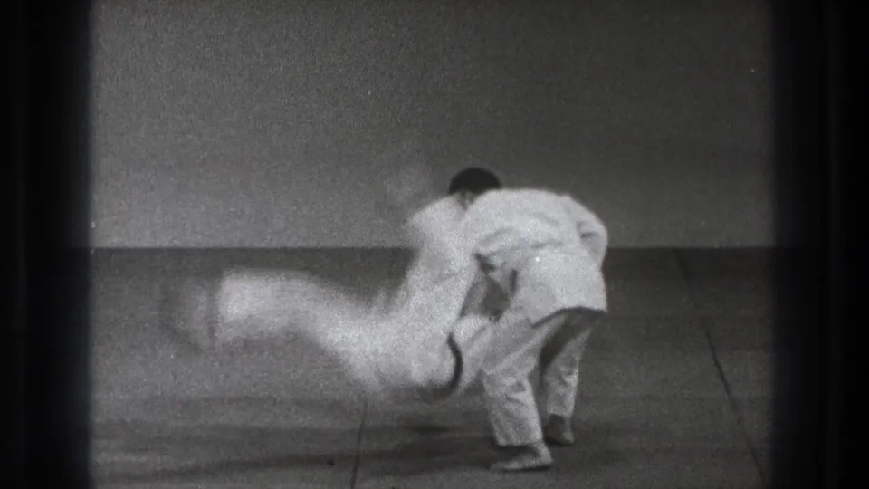 The thrown practitioner blurs downward toward the mat while his partner controls the motion in the 1971 Tokyo judo footage.