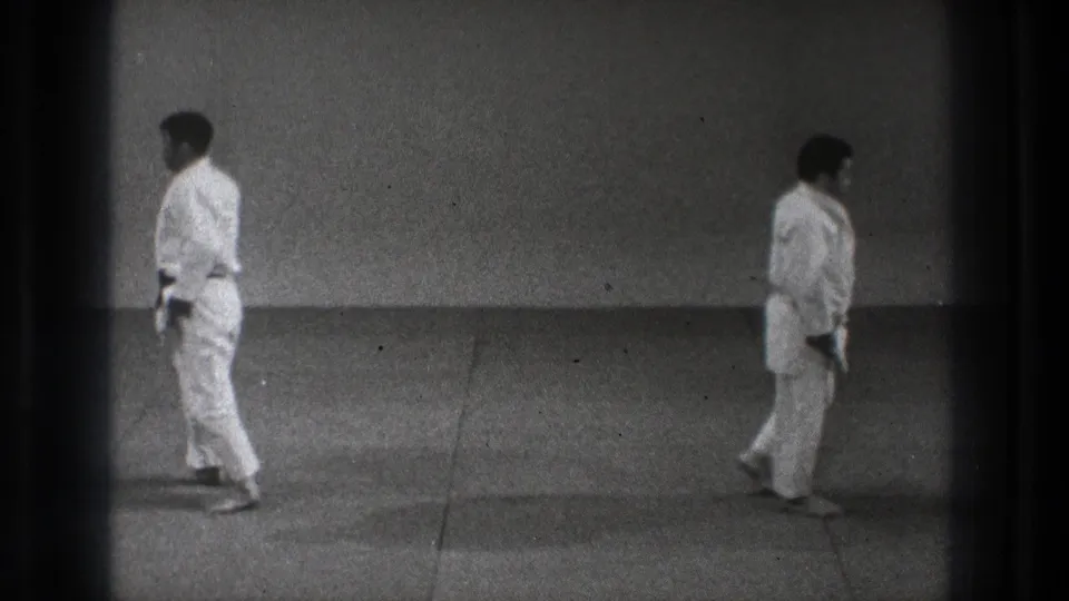 At the end of the 1971 Tokyo judo practice clip, two adult men in white uniforms walk away from each other across the tatami.