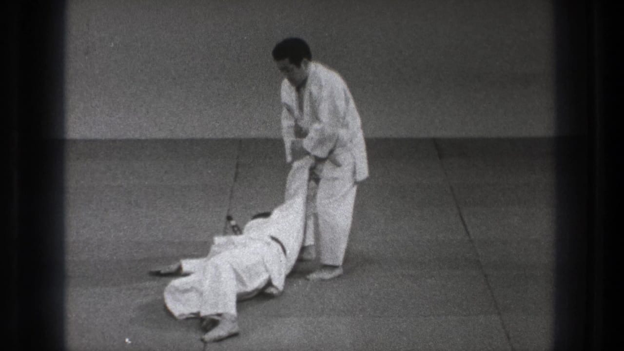 During the Tokyo 1971 judo practice sequence, one man is down on the mat as the standing partner controls his leg.