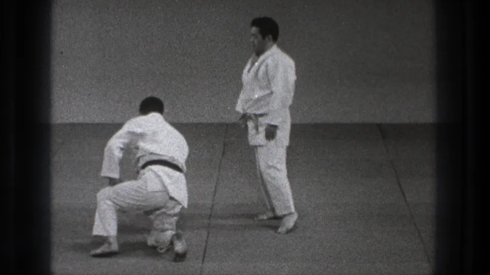 In the final frame, one judo practitioner kneels or rises from the mat while the other stands in a plain Tokyo training hall setting.